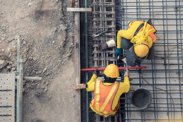 Zwei Bauarbeiter mit Warnwesten und Helmen führen Betonarbeiten auf einer Baustelle aus – professionelle Ausführung bei Dahl Bau