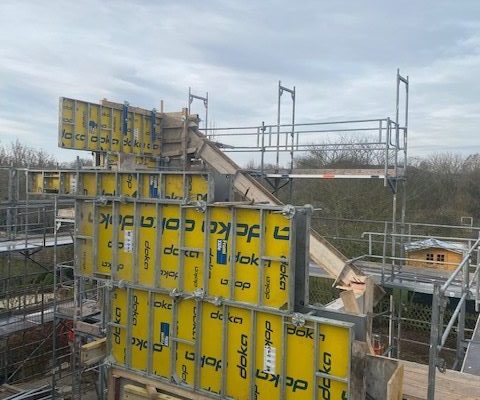 Gelbe Doka-Schalungselemente und Gerüste für eine Betontreppe auf einer Baustelle – Rohbau bei Dahl Bau