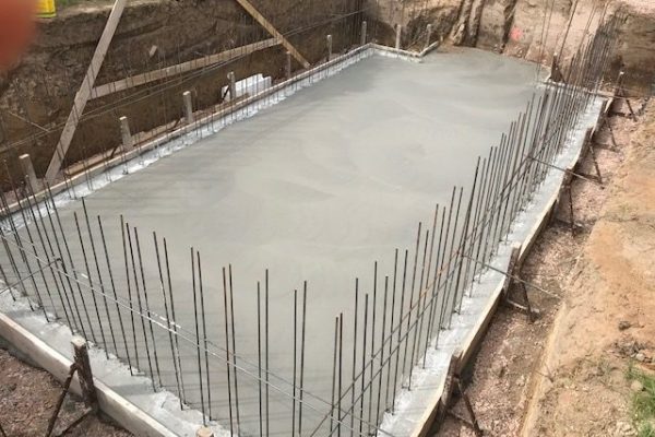 Frisch betonierte Bodenplatte mit senkrechter Bewehrung in einer Baugrube – Fundamentarbeiten von Dahl Bau