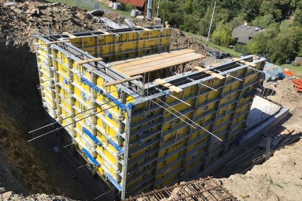 Massive gelbe Doka-Wandschalung in einer tiefen Baugrube – Betonvorbereitung durch Dahl Bau