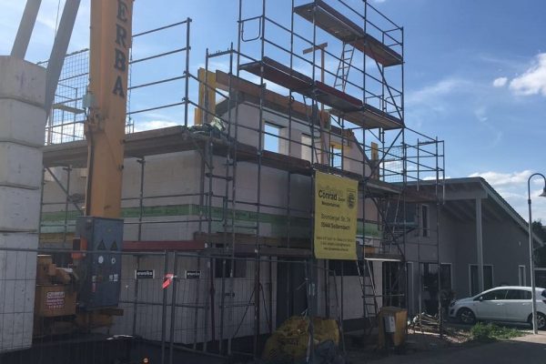 Eingeschaltes Wohnhaus im Rohbau mit Baukran und Gerüst – Baustelle eines Neubaus von Dahl Bau