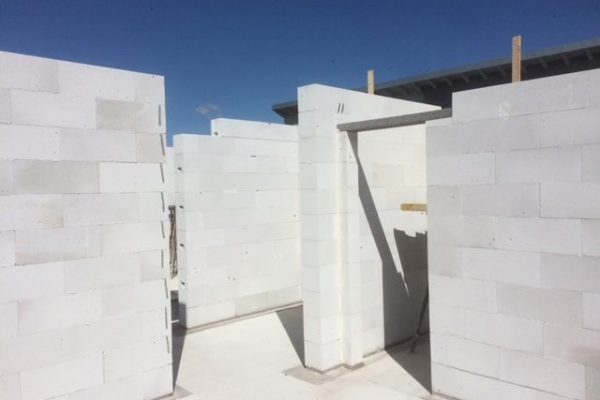 Rohbau mit weißen Porenbetonwänden und offenem Türdurchbruch – Mauerarbeiten bei sonnigem Wetter