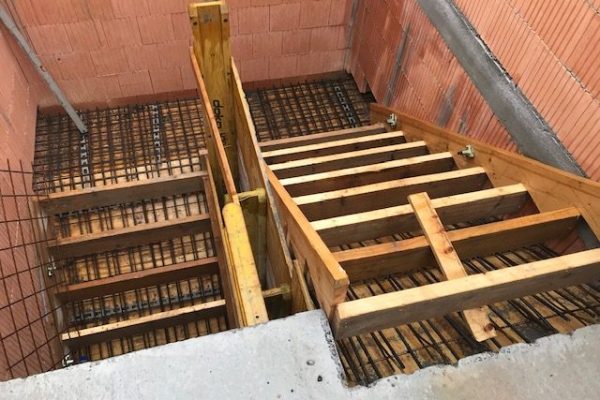 Holzschalung für Betontreppe mit sichtbarer Bewehrung in einem Mauerwerksschacht – Treppenbau im Rohbau