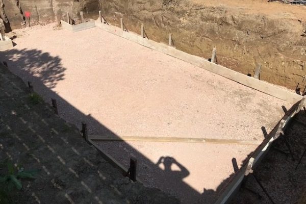 Rechteckige Baugrube mit verdichtetem Schotterbett und Schalung – Fundamentvorbereitung durch Dahl Bau