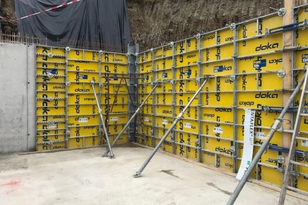 Gelbe Doka-Schalung an zwei Betonwänden mit Stützkonstruktion – Baustellenansicht im Rohbau